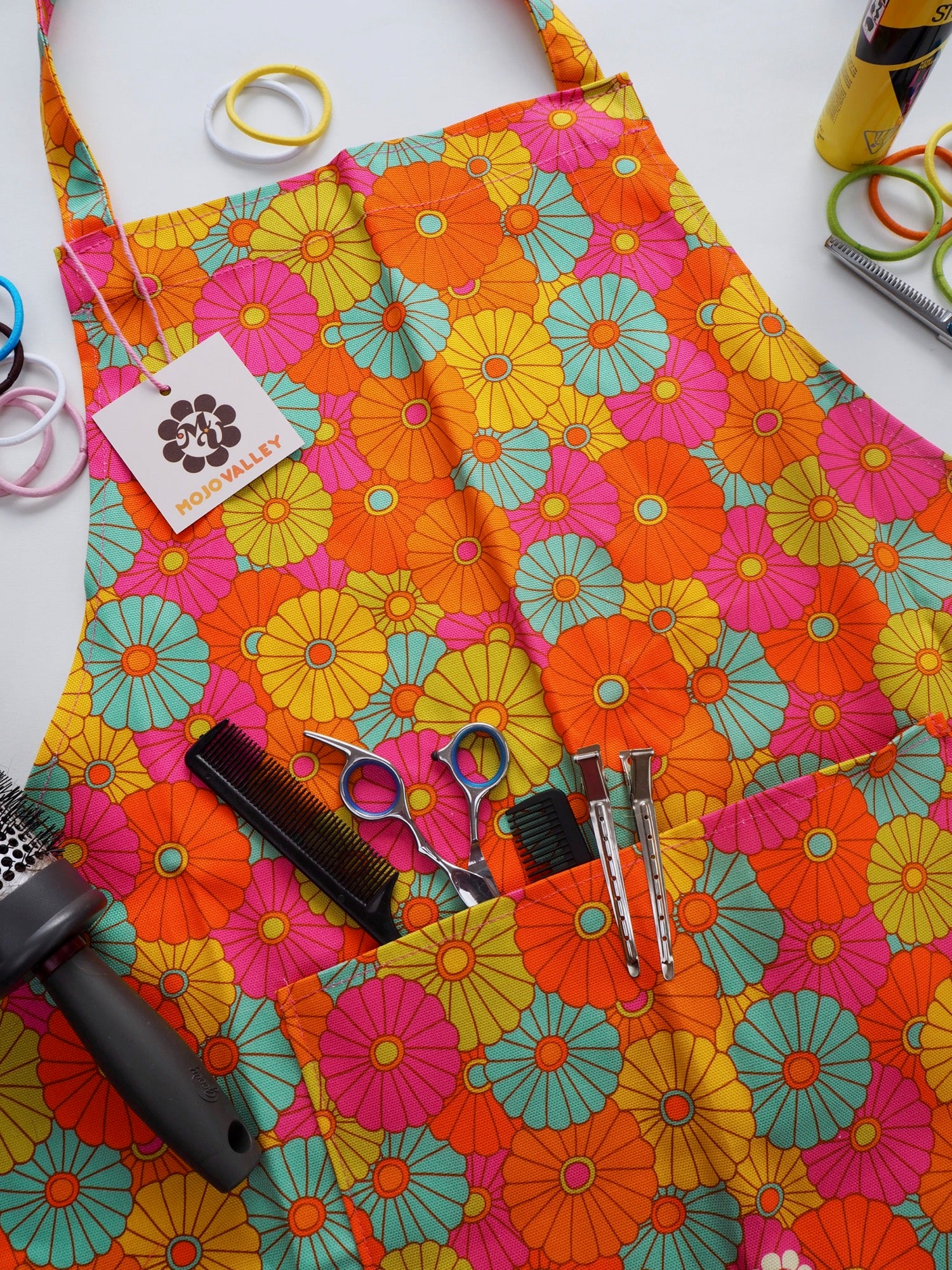 Rainbow colours of yellow, orange, blue, pink and green in a floral patten on an apron with a pocket 
