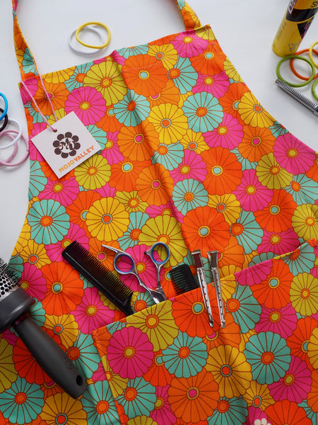Rainbow colours of yellow, orange, blue, pink and green in a floral patten on an apron with a pocket 