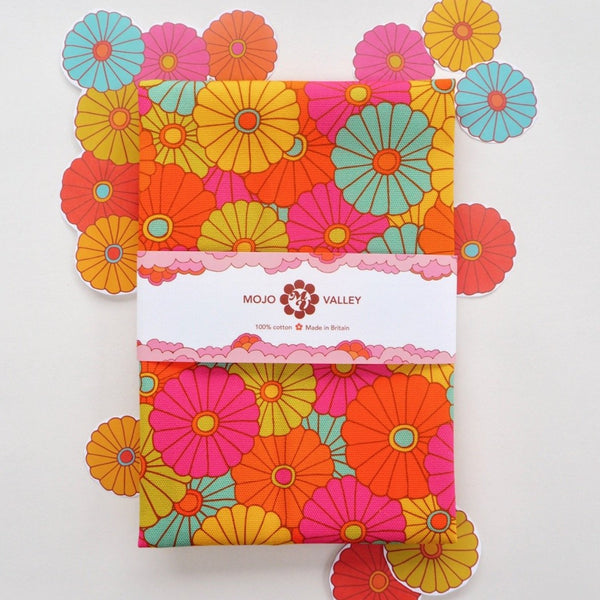 A floral rainbow patterned tea towel in the colours pink, orange, yellow, green and blue